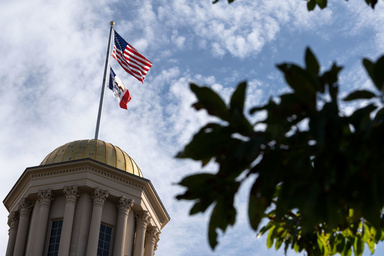 Fall campus scene of Old Capitol dome with US and Iowa flags